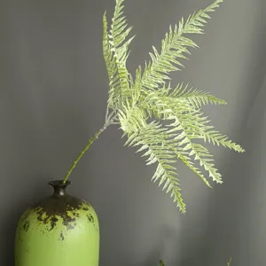 Detailed view of artificial fern branch in green vase, perfect for home decor and indoor settings.