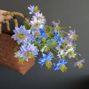 Detailed view of artificial wildflowers in a woven bamboo basket for home decor props setup.