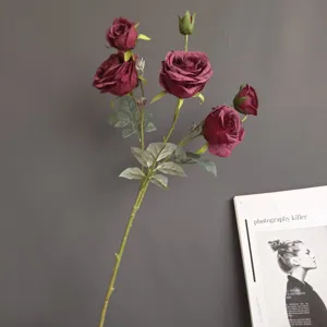 Detailed close-up of artificial rose flower branch showing dark red petals and realistic leaves.