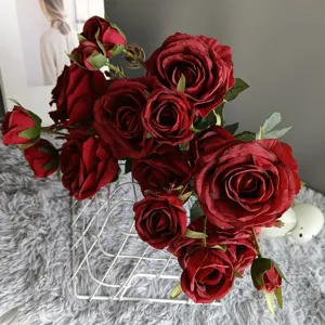 Closeup of dark red artificial rose bouquet with burnt edges placed in white wire basket.