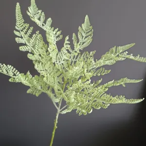 Artificial fern branch detail, soft green plastic plant for home decor and wedding arrangement.