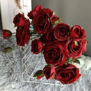 Close-up detail view of deep red artificial velvet roses bouquet in modern home decor scene.