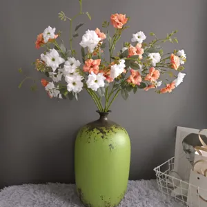 Close-up detail of artificial wild roses in a rustic green vase for Nordic home decor setup.