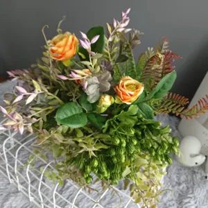 Détail de bouquet de fleurs artificielles, roses orange vibrantes et verdure déco.