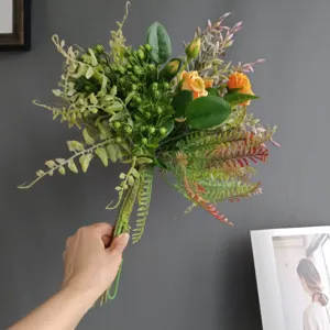 Détail de bouquet de fleurs artificielles avec de jolies roses orange et feuillage vert.