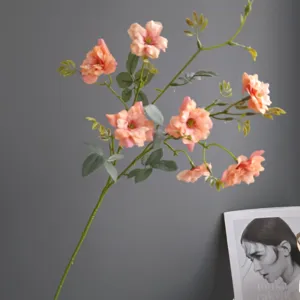Detailed shot of artificial wild rose stem with delicate cream pink petals and green leaves.