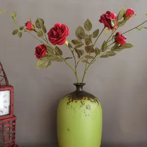 Künstlicher roter Rosenstrauß mit grünen Blättern in Vintager Keramikvase für Wohndekor.