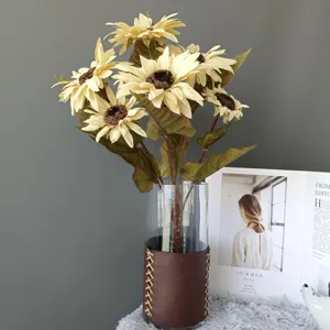 Vista dettagliata di un mazzo di girasoli artificiali in vaso di vetro con rivestimento in pelle.
