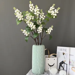Artificial white berry branch in light green vase for Nordic home decor and interior staging detail view