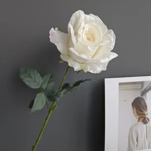 Primer plano detallado de rosa blanca artificial con bordes quemados y tallo verde oscuro.