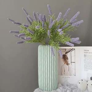 Kuenstlicher Lavendel Blumenstrauss in strukturierter gruener Keramikvase fuer Wohndekor Detail.