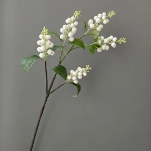 Close-up detail of artificial white berry branch, featuring foam berries and green leaves.