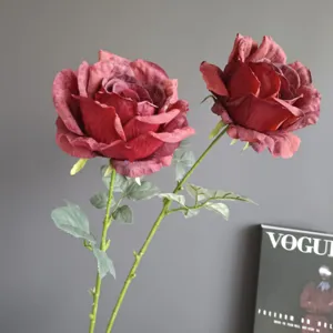 Detalle en primer plano de rosas artificiales burdeos retro con tallos verdes para decoración.
