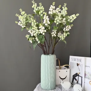 Artificial white berry branches in light green ribbed ceramic vase for Nordic home decor detail