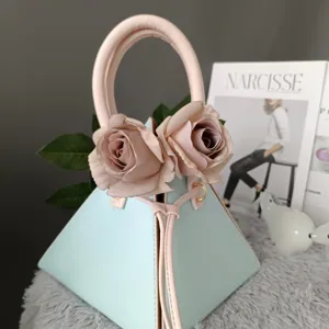 Primer plano de un bolso de mano piramidal único con asa rosa y elegante decoración de rosas.