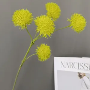Detail view of artificial yellow pompon flower branch, plush decorative botanical prop for home.