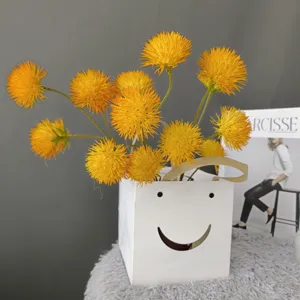 Artificial yellow dandelions flower balls detail view in white smiley bag for home decor