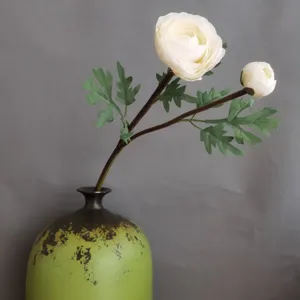 Close-up of white artificial ranunculus flower stem in a ceramic vase for home decor