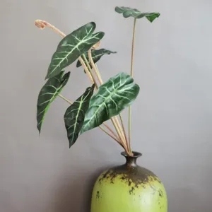 Detalle de planta artificial hoja de oreja de elefante verde para decoración interior.
