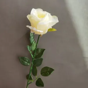 Gros plan détaillé d'une tige de rose blanche artificielle, montrant des feuilles réalistes.