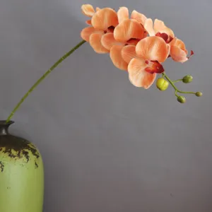 Detailansicht künstlicher orangefarbener Phalaenopsis Orchidee in Keramikvase für Dekoration.