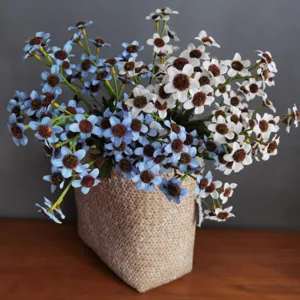 Close-up detail of artificial blue and white daisies with flocked centers in woven pot decor.