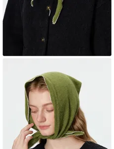 Détail d'une écharpe triangulaire en tricot vert, texture douce avec bordure festonnée blanche.