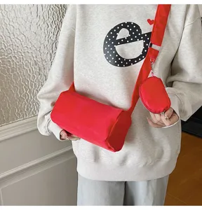 Close-up of a stylish red nylon cylindrical crossbody shoulder bag with coin purse.