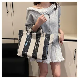 Detail shot of the black and white striped coated canvas tote bag featuring clear layer and text.