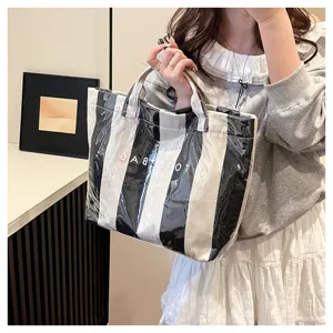 Close-up view of the chic black and white striped coated canvas tote bag showing letter print detail.