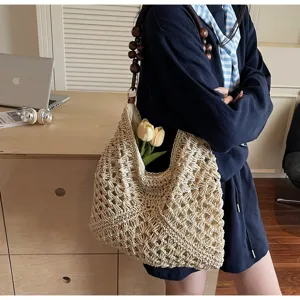 Detail shot of hollow hand-woven straw shoulder bag with beaded strap for beach vacation style.