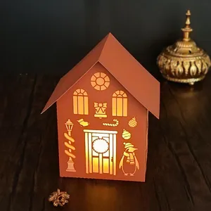 Detailed close-up of the laser-cut paper Christmas house night light glowing warmly.