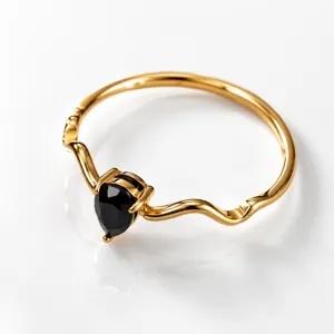 Detailed view of the gold wavy ring featuring a black pear-shaped zirconia stone.