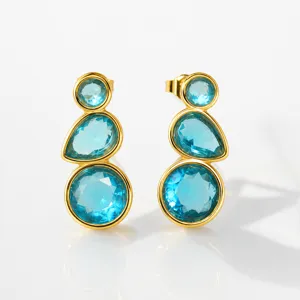 Close up detail of triple blue stone drop earrings with gold plated metal setting.