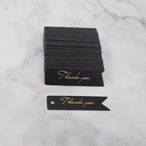 Black swallowtail paper hang tags detail with gold foil thank you text for gift wrapping.