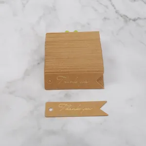 Detail view of brown kraft paper thank you tag with gold foil lettering and swallowtail.
