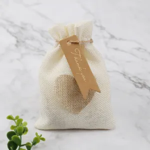Burlap gift pouch detail shot with heart decoration and thank you hang tag on marble background