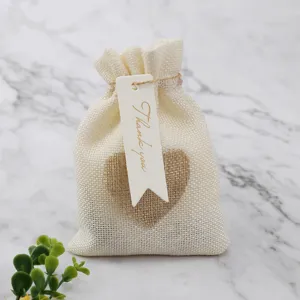 Close-up detail shot of rustic beige linen burlap favor pouch with heart patch and tag.