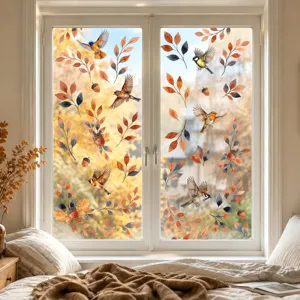 Detail of autumn window stickers with watercolor birds and falling leaves on clean glass surface.