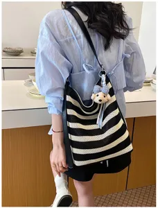 Detailed view of a casual black and white striped hollow woven shoulder bag lifestyle shot.