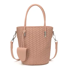 Vista dettagliata della borsa a secchiello intrecciata rosa, con elegante motivo in pelle.