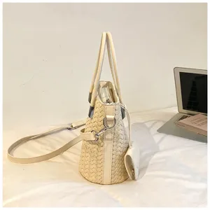 Vista laterale dettagliata della borsa a secchiello intrecciata beige con manici e tracolla.