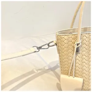 Vista dettagliata della borsa a secchiello intrecciata beige con tracolla e dettagli.