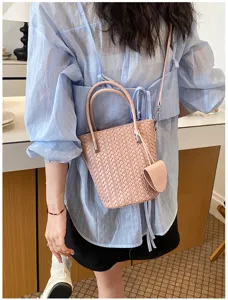 Borsa a secchiello intrecciata rosa chic con manico elegante e tracolla pratica.