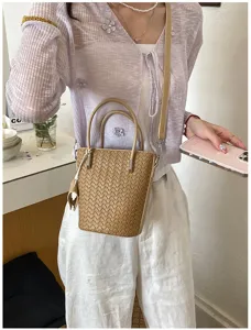 Dettaglio della borsa a secchiello intrecciata elegante con manico in pelle e tracolla.