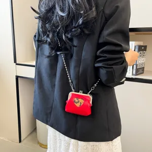 Mini red kiss-lock crossbody bag with leopard heart detail and sleek metal chain strap.