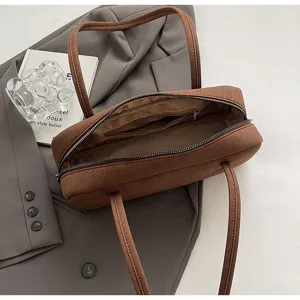Detail view of brown suede baguette shoulder bag, minimalist design, soft interior lining.