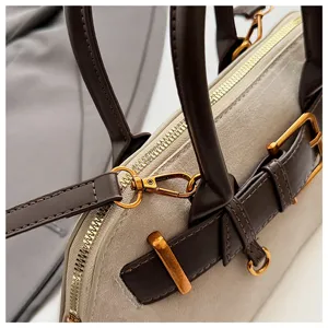 Detailansicht der Wildleder Handtasche mit goldfarbenen Beschlägen und edlem Schnallenriemen.