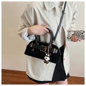 Detailansicht der schwarzen Wildledertasche mit Schnallendesign und niedlichem Hundeanhänger.