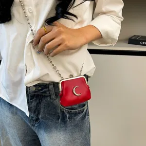 Mini red kiss-lock crossbody bag with metal crescent moon charm and chain strap for women.